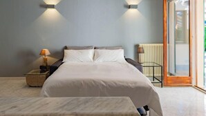 A modern bedroom with a large bed, two wall-mounted lights, a bedside table with a lamp, and a view through a glass door. - Stazione by Interhome (Porlezza)