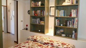 Ein Schlafzimmer mit einem Bett, zwei Bücherregalen, einem Nachttisch und einer Tür.