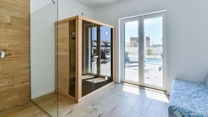 Una habitación moderna con un armario de madera, una puerta de cristal que da a un balcón y vistas a la piscina.