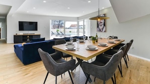 Un comedor moderno con una mesa de madera dispuesta para seis personas, rodeada de sillas tapizadas en gris.