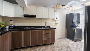 Une cuisine moderne avec des meubles en bois, un plan de travail noir, une cuisinière encastrée, un évier et un chauffe-eau.