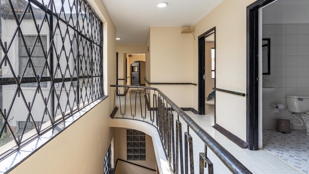 Un intérieur à plusieurs niveaux comprenant un escalier, une fenêtre avec une grille en métal et une salle de bain avec des toilettes et un lavabo.