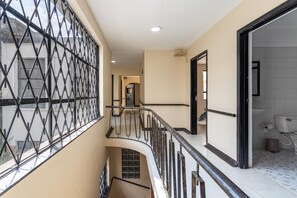A multi-level interior with a staircase, a window with a metal grille, and a bathroom with a toilet and sink. - TRIBU18 (Bogotá)