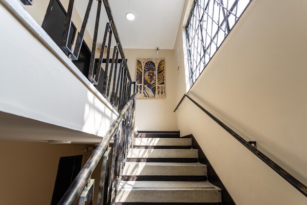 A staircase with metal railings and a wall-mounted artwork. - TRIBU18 (Bogotá)
