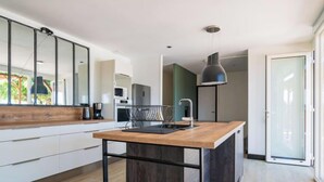 Una cocina moderna con una isla de madera, armarios blancos y un ventanal grande.