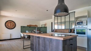 Una cocina moderna con una isla central, un reloj grande en la pared y un microondas sobre los armarios.
