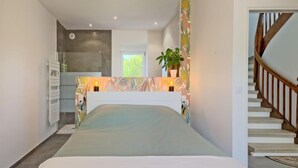Un dormitorio con una cama, un escritorio pequeño, una planta en maceta y una escalera.