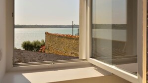 Una habitación con un ventanal grande que da a una masa de agua y un horizonte lejano de la ciudad.