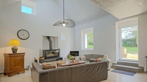 Un salón espacioso con sofá, televisor, chimenea y un ventanal grande.