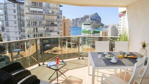 Ein Balkon mit Esstisch, gedeckt für das Frühstück, mit Blick auf eine felsige Küstenlinie und weitere Gebäude.