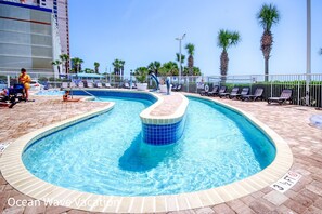 Una piscina de diseño curvo, rodeada de sillones de descanso y palmeras.