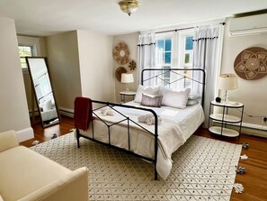 A neatly arranged bedroom with a bed, bedside tables, a mirror, and decorative wall art. - Downtown Historical Bristol Seaside cottage w front row seats to 4th July Parade (Bristol)