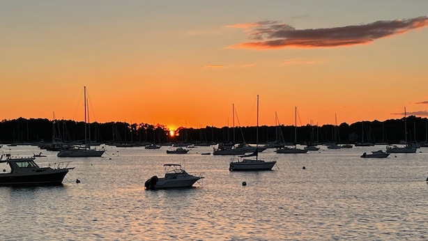 Un port de plaisance où de nombreux bateaux sont amarrés au coucher du soleil.