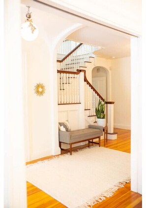 Staircase leads to an upper level with a bench and potted plant.