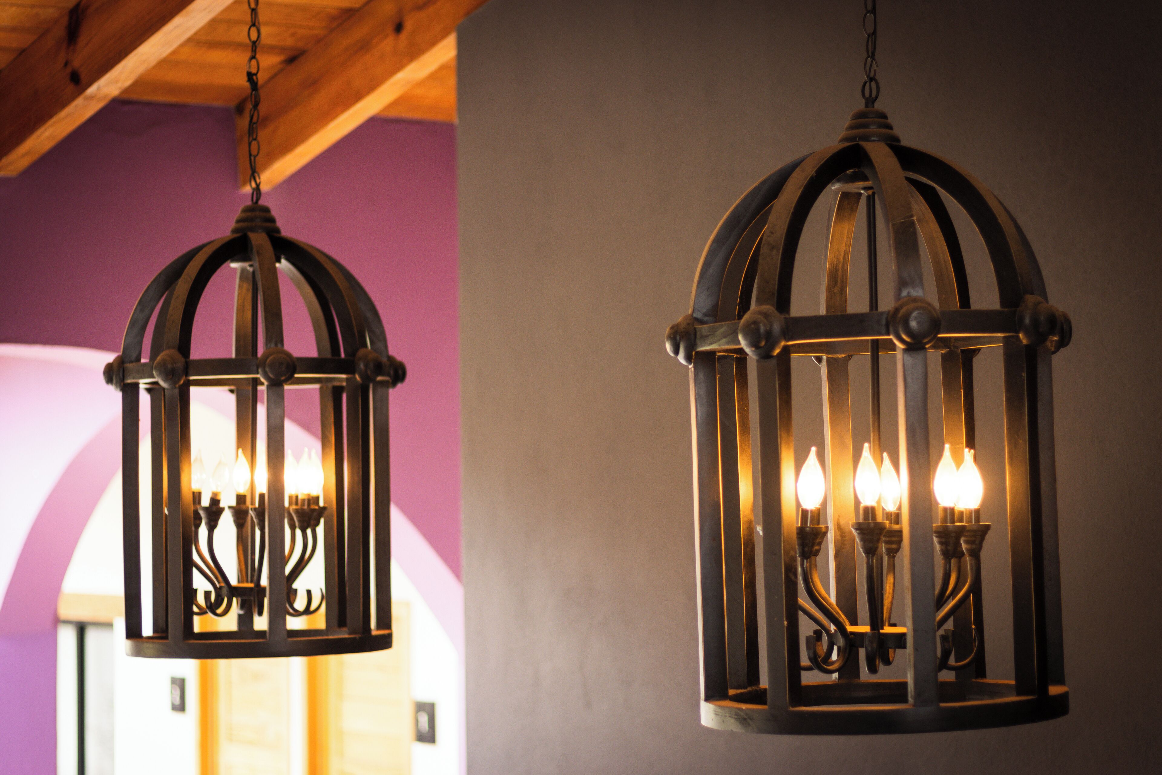 Two hanging lantern-style light fixtures with multiple bulbs, suspended from a ceiling with exposed wooden beams.
