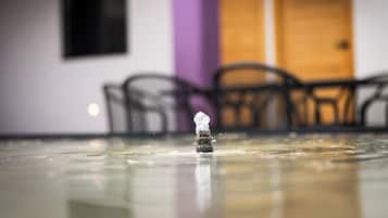 A small figurine on a reflective surface with a blurred background of chairs and a door.