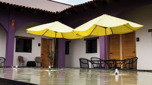 Zona de piscina con sombrillas amarillas, sillas y una puerta de madera.
