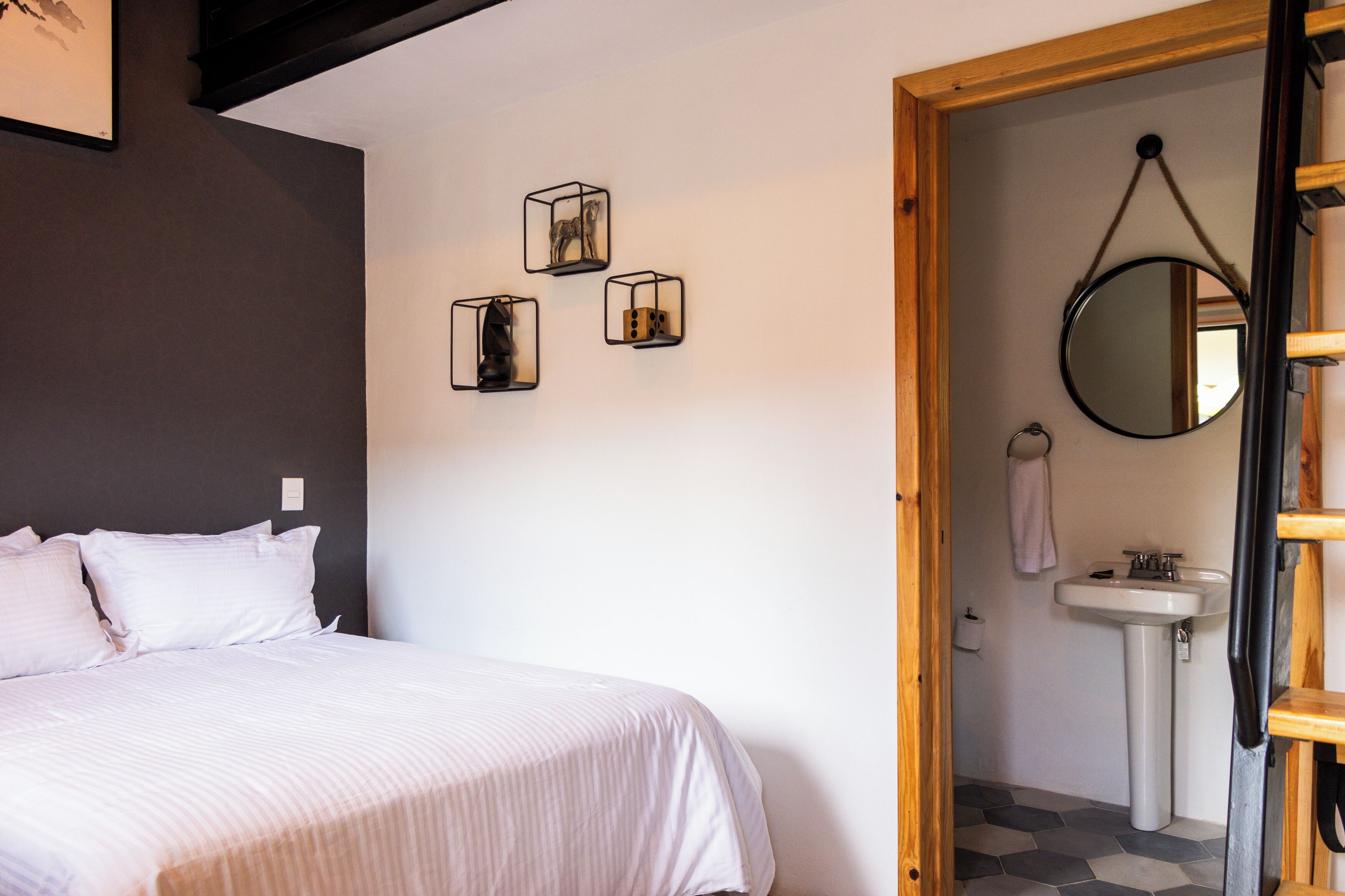 A bedroom with a bed, a wall-mounted mirror, and three cube-shaped light fixtures.