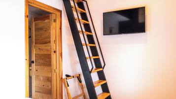 A wooden door, a black metal ladder, and a flat-screen TV mounted on a wall.