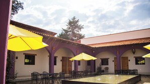 Un patio con mobiliario exterior, una fuente central y techo de baldosas.