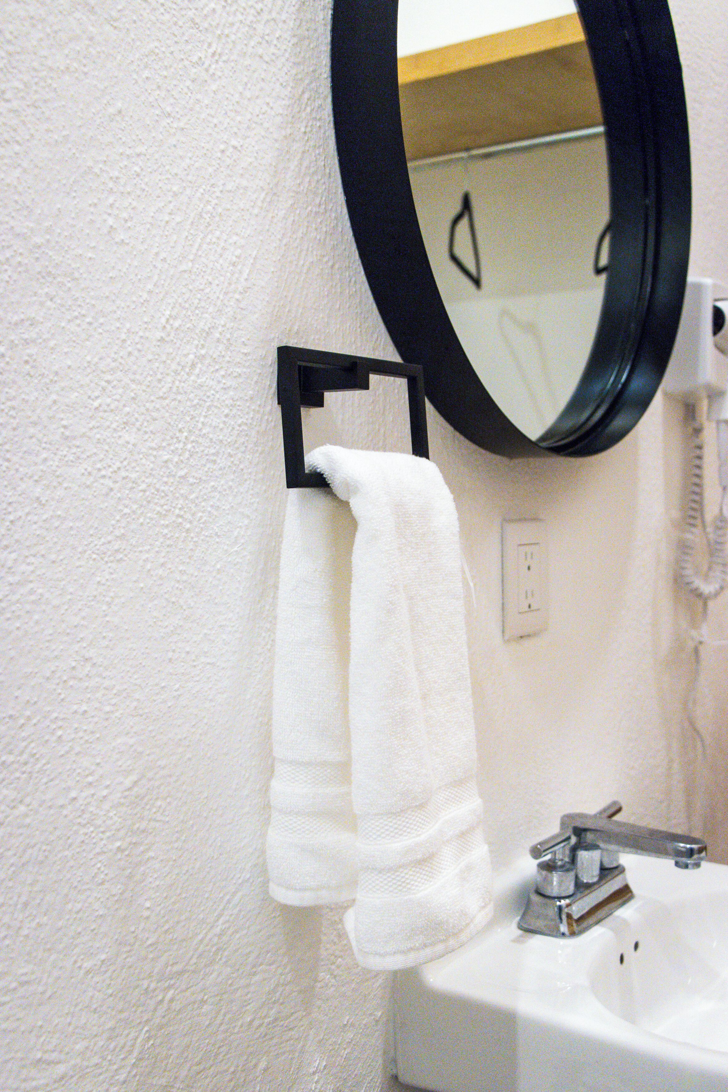 A bathroom with a white sink, a black towel rack, and a mirror.