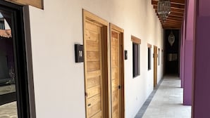 Un pasillo con puertas de madera, letreros numerados y piso de baldosas.