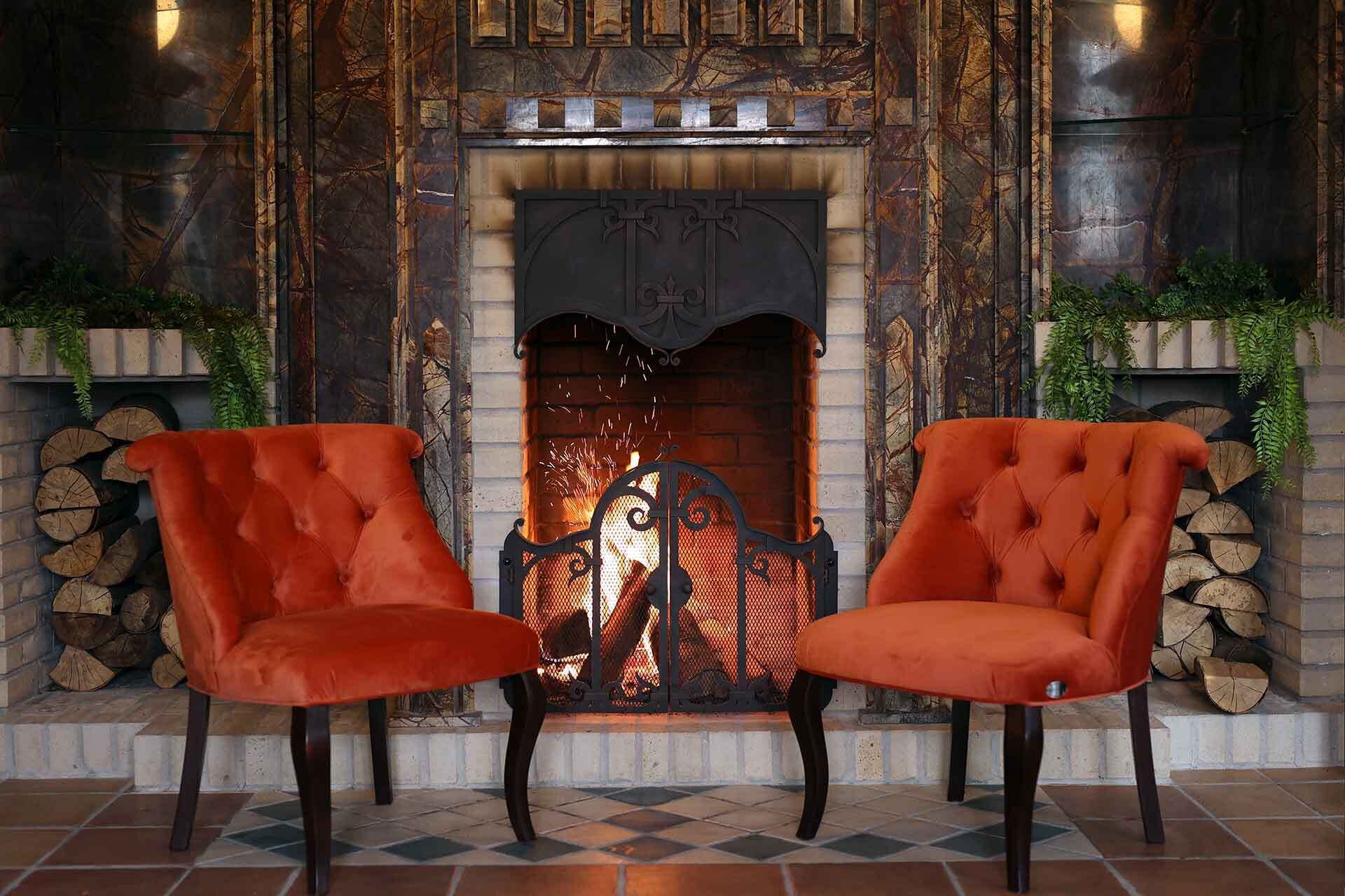 A fireplace with a decorative metal grate, flanked by two upholstered chairs with dark legs.