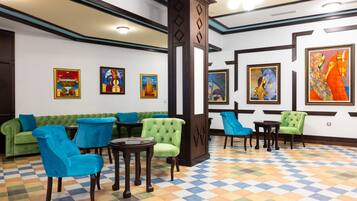 A lobby with a green sofa, blue chairs, and a checkered floor.