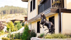A building with a balcony, a horse statue, and a garden. - Armaco Residence (Koprivshtitsa)