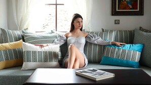 A person sitting on a patterned sofa with a book on a table in front. - Armaco Residence (Koprivshtitsa)