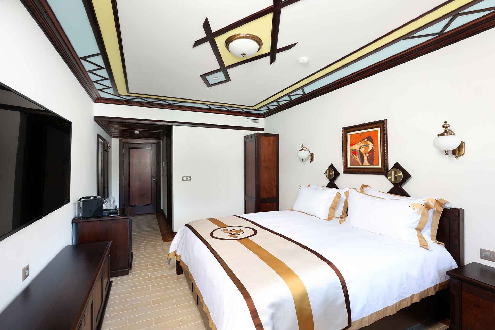 Habitación de hotel con una cama grande, un escritorio, un armario y una puerta que da a otra habitación.