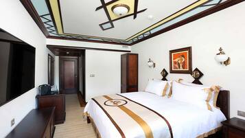 Habitación de hotel con una cama grande, un escritorio, un armario y una puerta que da a otra habitación.