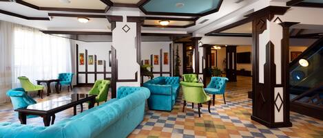 A lobby with a checkered floor, blue and green seating, and a staircase.