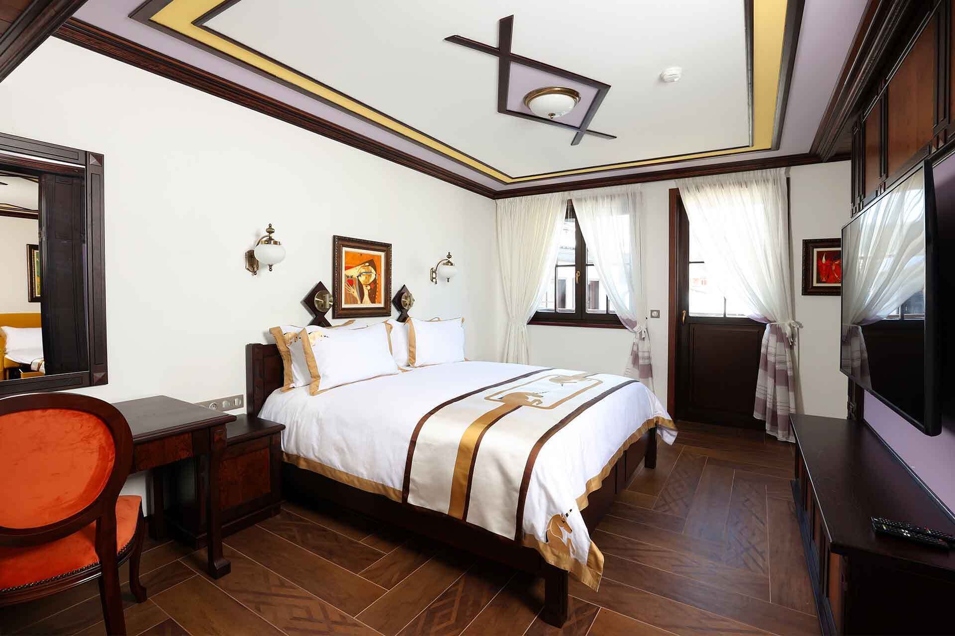 Habitación de hotel con una cama grande, un escritorio con silla, televisor y espejo.