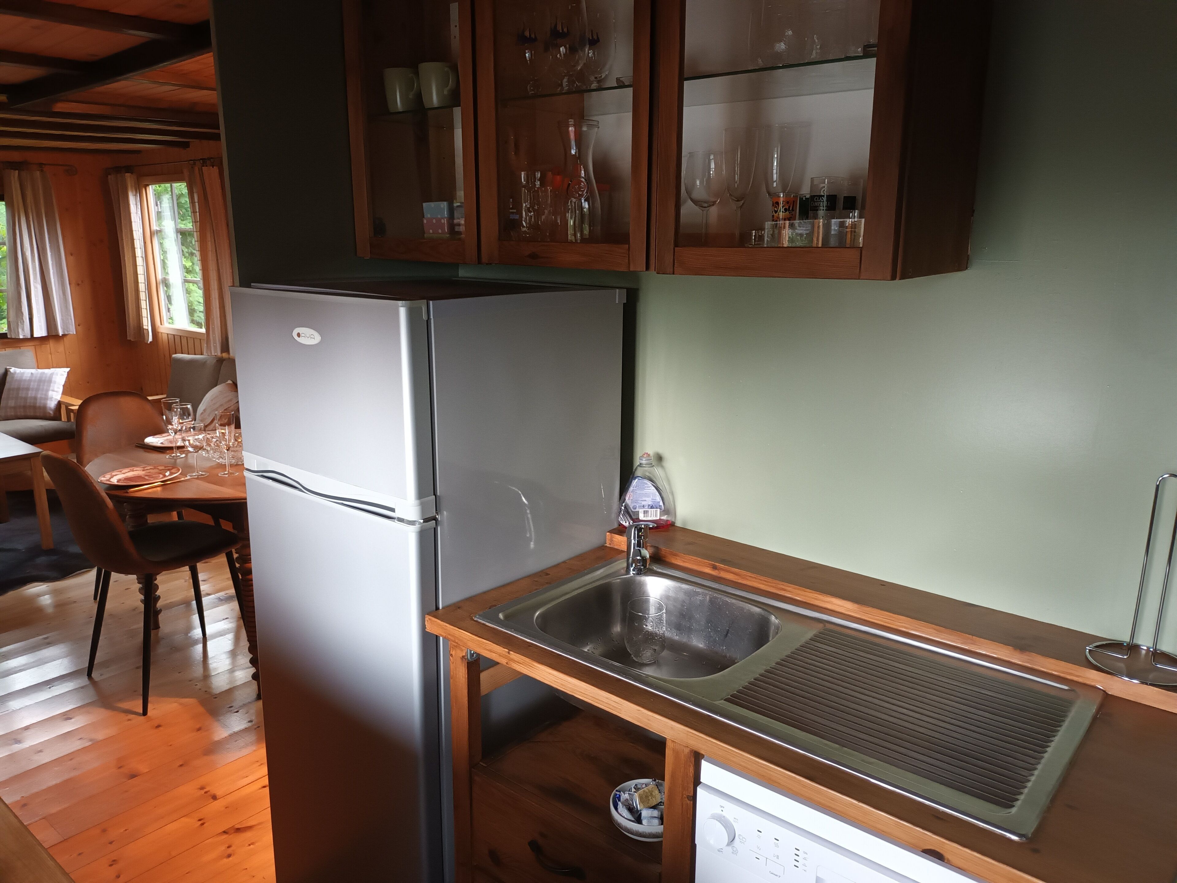 A compact kitchen with a refrigerator, a sink, and wooden cabinets.