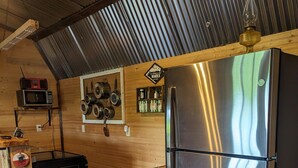 Una cocina compacta con refrigerador de acero inoxidable, armarios de madera y un microondas en un estante.