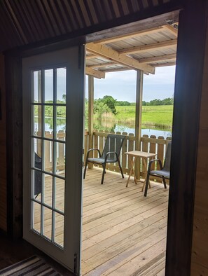 Una terraza de madera con vista a un lago y campos cubiertos de hierba.