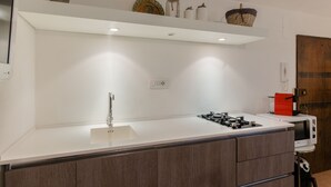 Een moderne keuken met een wit aanrecht, een gasfornuis, een magnetron en een houten kast.