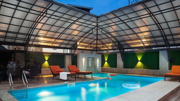 Una piscina interna con lettini e struttura a soffitto in vetro.