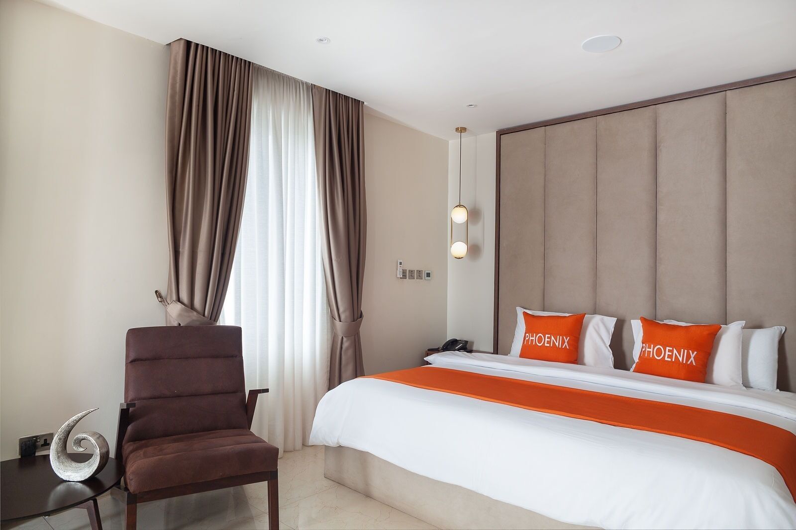 A hotel room with a bed, a chair, a desk, and a nightstand.