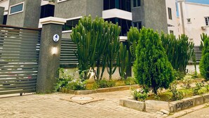 Una casa moderna a due piani con il numero '4' ben visibile su un pilastro, circondata da vegetazione rigogliosa e un vialetto lastricato.