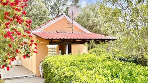 A small building with a red-tiled roof, surrounded by lush greenery and a flowering tree. - Renas Studio near Roda (Roda)