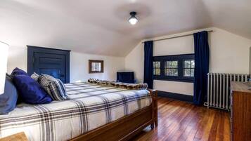A bedroom with a wooden bed, a radiator, a window with curtains, and a ceiling light.