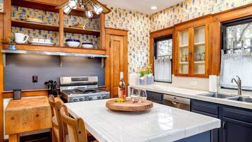 A kitchen with wooden cabinets, a central island, a stove, and a window with curtains.