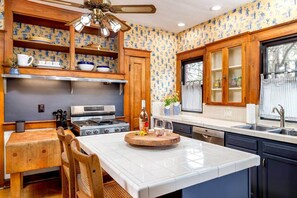 A kitchen with wooden cabinets, a central island, a stove, and a window with curtains.