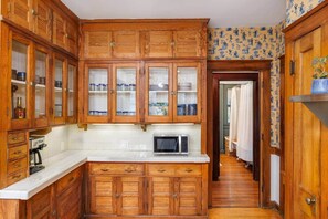 Cucina con pensili in legno, forno a microonde e pannelli decorativi in piastrelle.