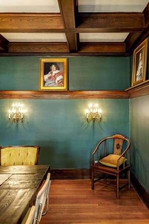 Una sala da pranzo con tavolo e sedie in legno, un lampadario e applique a parete.