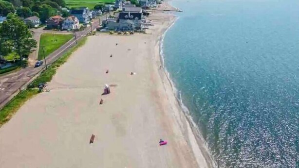 Vista aérea de un pueblo costero con playa, casas y una carretera.