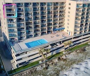 Un hôtel à plusieurs étages doté de balcons, d’une piscine sur le toit et d’un parking.