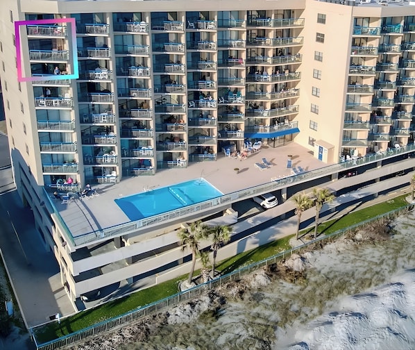 A multi-story hotel with balconies, a rooftop pool, and a parking area. - WOW Panoramic Oceanfront Corner Condo/Oceans #1016/Walk to Dining &Grocery (North Myrtle Beach)